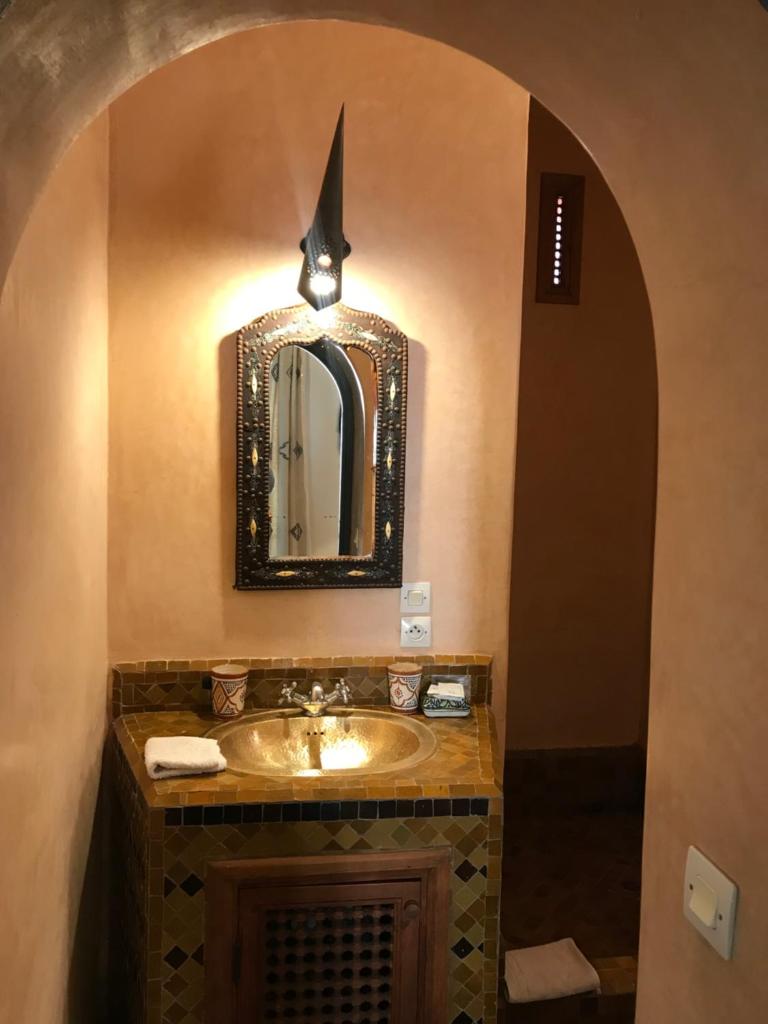 La salle de bains est pourvue d'un lavabo et d'un miroir en forme de requin. dans l'établissement Riad Sahara Nour, à Marrakech