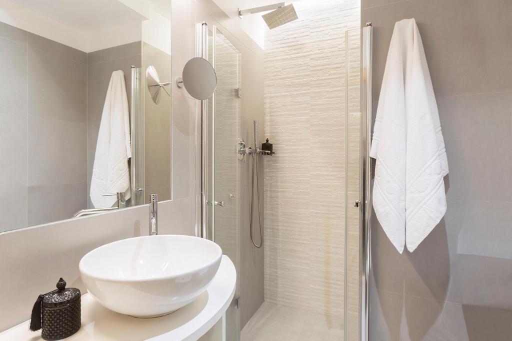 une salle de bain blanche avec lavabo et douche dans l'établissement Hotel Commodore, à Riccione