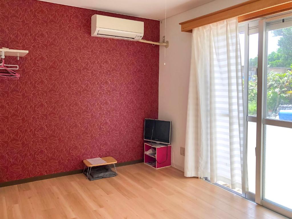 Il comprend un salon doté d'une télévision et d'un mur rouge. dans l'établissement Minshuku Irayoi, à Ishigaki