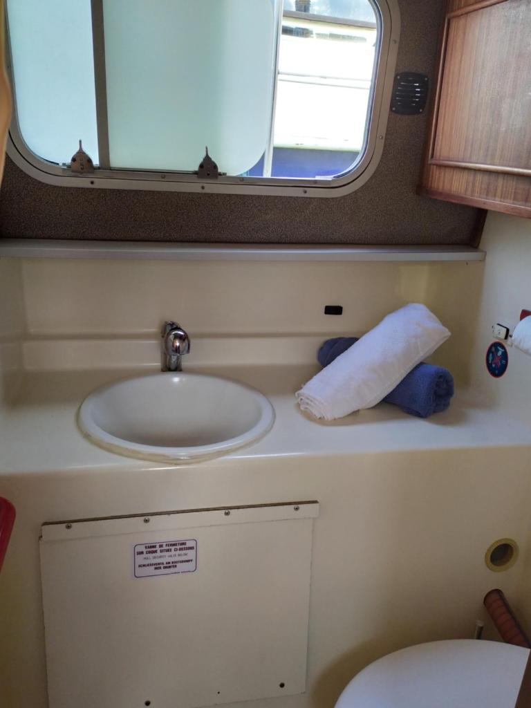une petite salle de bain avec un lavabo et une fenêtre dans l'établissement Penichette habitable max 4-5 pers terrasse vue sur l'eau ST JEAN DE LOSNE, à Saint-Jean-de-Losne