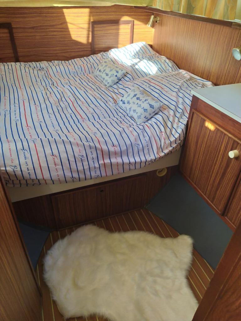 - un petit lit dans un bateau avec un tapis blanc dans l'établissement Penichette habitable max 4-5 pers terrasse vue sur l'eau ST JEAN DE LOSNE, à Saint-Jean-de-Losne