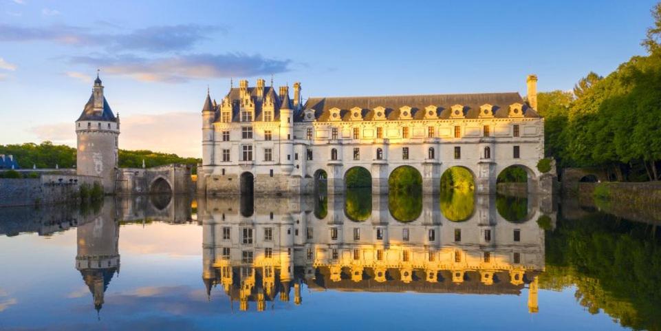 un château avec sa réflexion dans l'eau dans l'établissement Mobil Home tout confort 6 personnes avec wifi, à Onzain