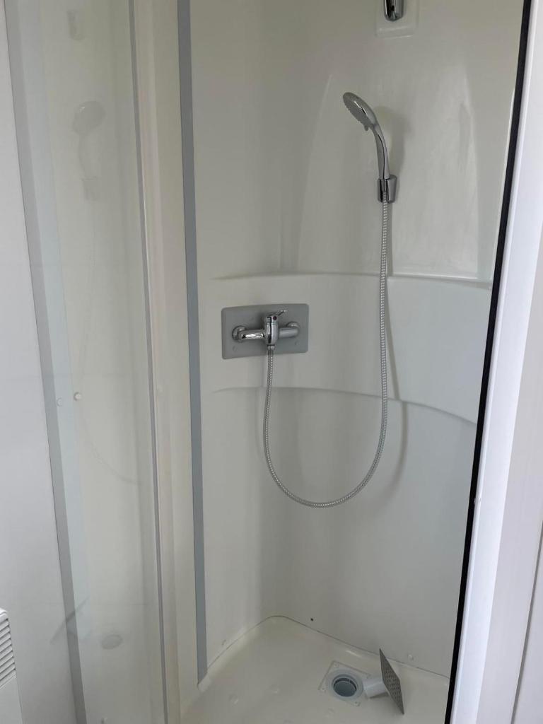 une douche avec une porte vitrée dans une salle de bain dans l'établissement Mobil Home tout confort 6 personnes avec wifi, à Onzain 7 autres photos
