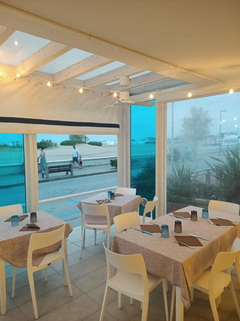 un restaurant avec des tables et des chaises et une vue sur l'océan dans l'établissement Hotel Verona, à Caorle