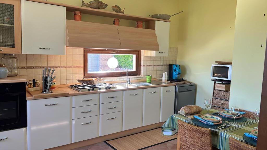 - une cuisine avec des placards blancs, un évier et une table dans l'établissement Villa Dolce Havana con piscina, à Sperlonga