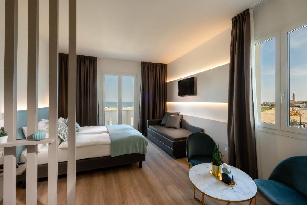 une chambre d'hôtel avec un lit et un canapé dans l'établissement Hotel Delfino, à Caorle