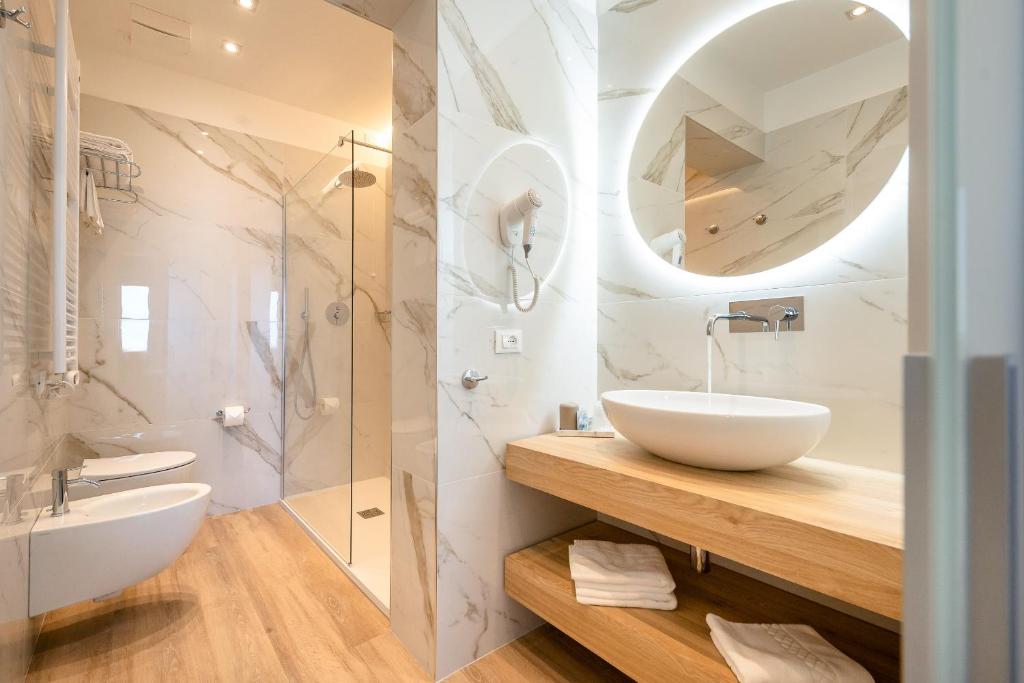 une salle de bain avec un lavabo et un miroir dans l'établissement Hotel Delfino, à Caorle