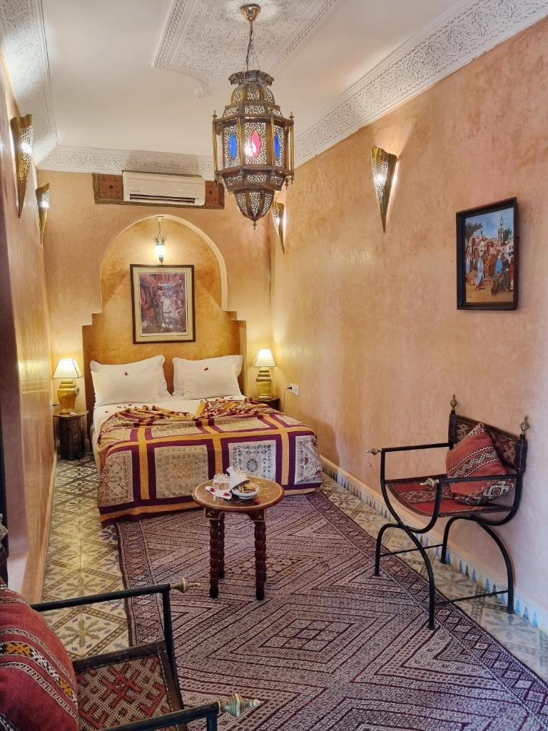 une chambre avec un lit, une table et un lustre dans l'établissement Riad Adriana, à Marrakech