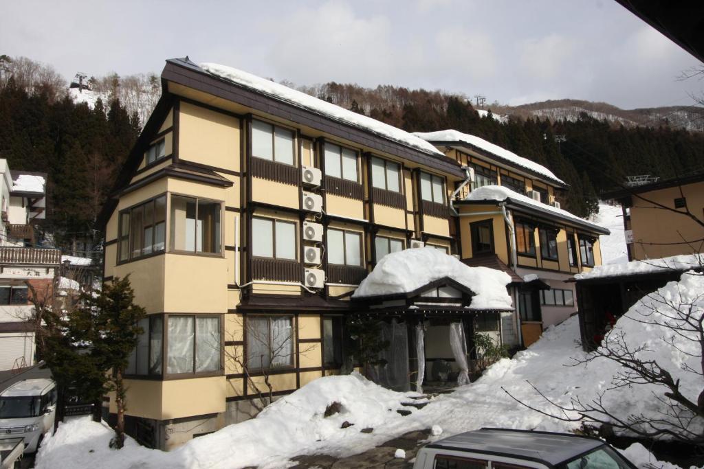 un grand bâtiment avec de la neige sur son côté dans l'établissement Kawahiro, à Nozawa Onsen
