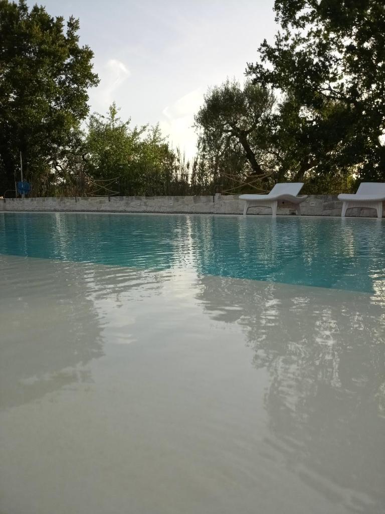 une piscine d'eau avec des chaises et des arbres dans l'établissement Trulli Volpe, à Alberobello 25 autres photos