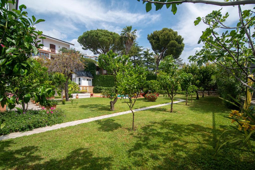 un jardin avec des arbres et un bâtiment en arrière-plan dans l'établissement Magnificent Villa Sanremo, à Sanremo