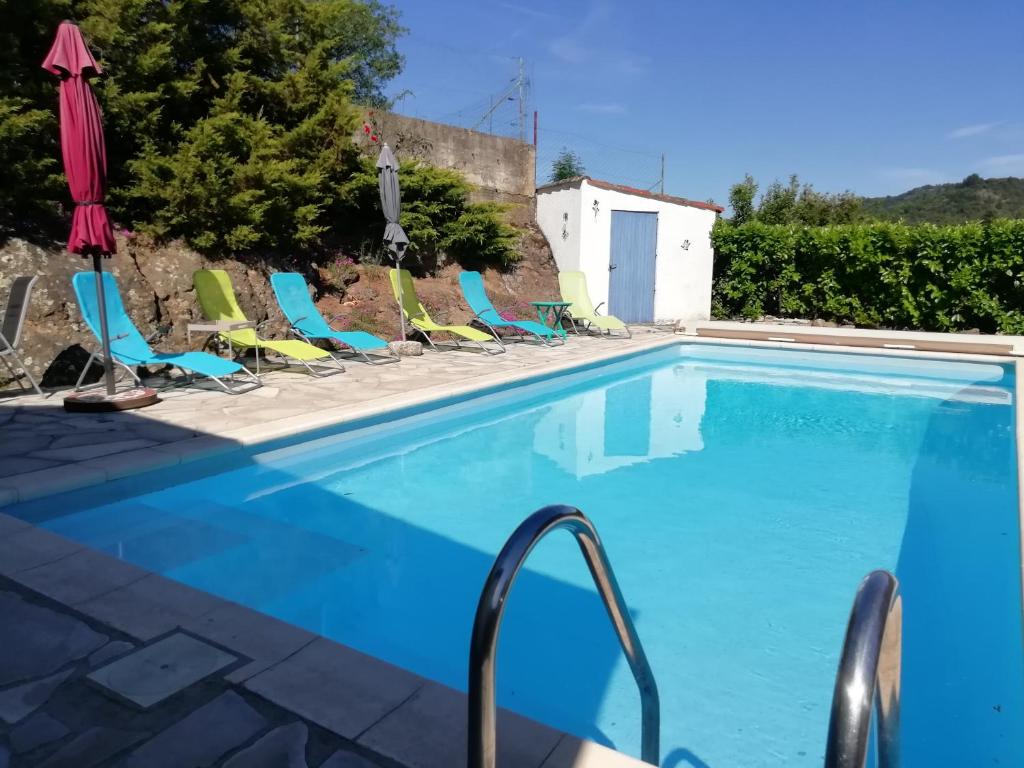 une piscine avec des chaises et un parasol dans l'établissement Gîte La nonnette, à Prades