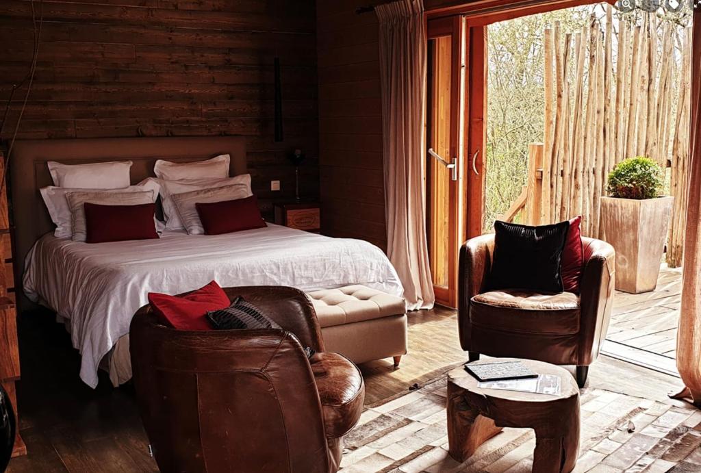 une chambre avec un lit et deux chaises dans l'établissement D'EMILION De SENS, à Gardegan-et-Tourtirac
