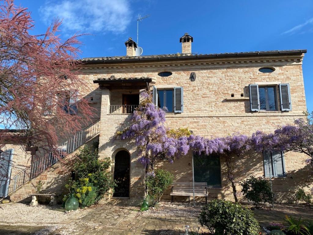une vieille maison en pierre avec des glycines violets sur elle dans l'établissement Casale Iris, à Belmonte Piceno