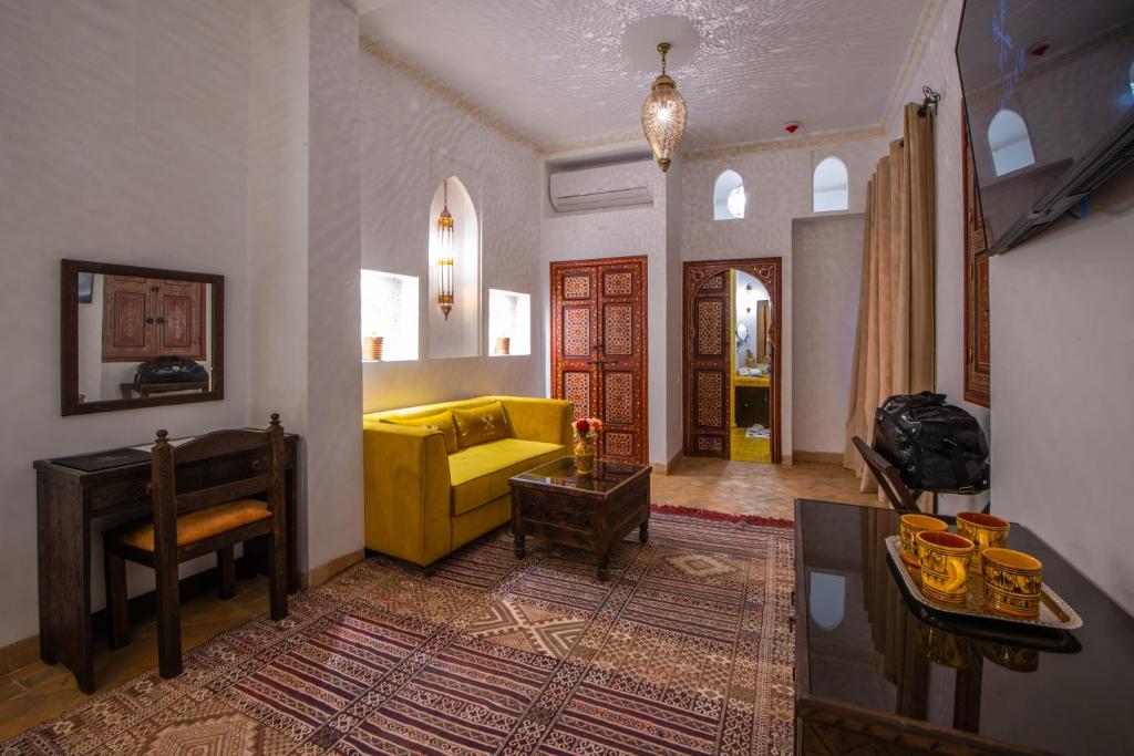 un salon avec un canapé jaune et une table dans l'établissement Riad la clé d'or & spa, à Marrakech