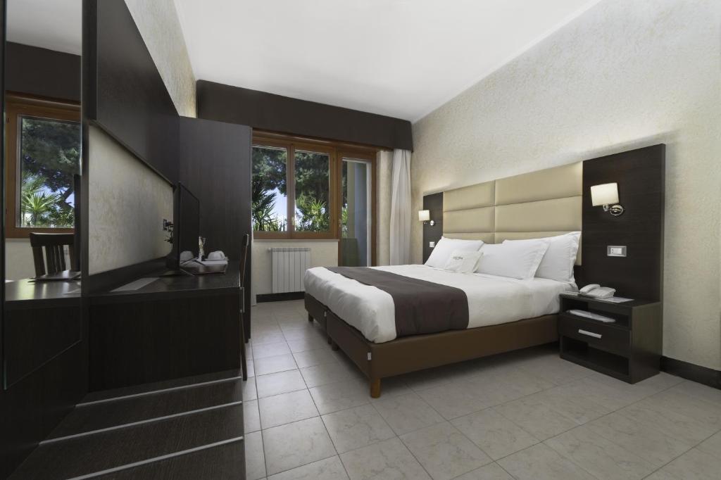 une chambre avec un grand lit et un bureau dans l'établissement Hotel Villa, à Bisceglie