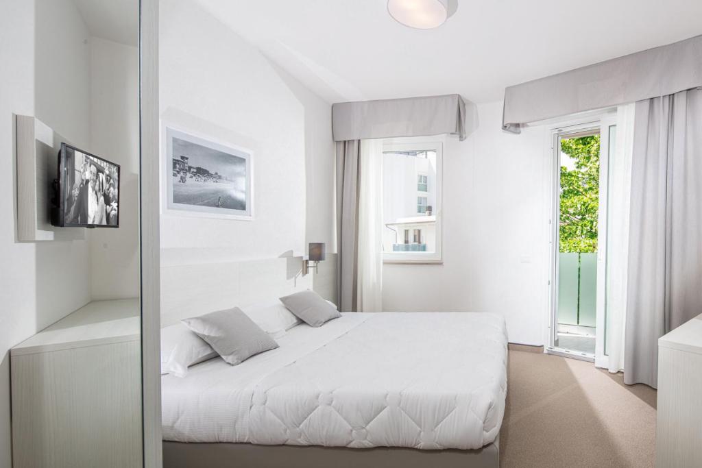 une chambre blanche avec un lit blanc et une fenêtre dans l'établissement Hotel Centrale, à Lignano Sabbiadoro 60 autres photos