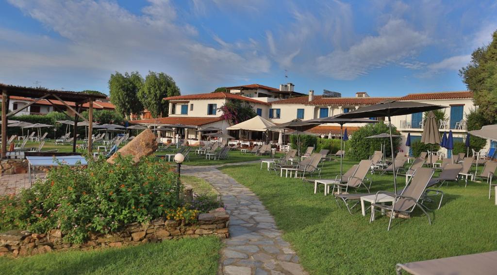 un groupe de chaises et de parasols dans une cour dans l'établissement IHR Hotel San Paolo, à Porto San Paolo