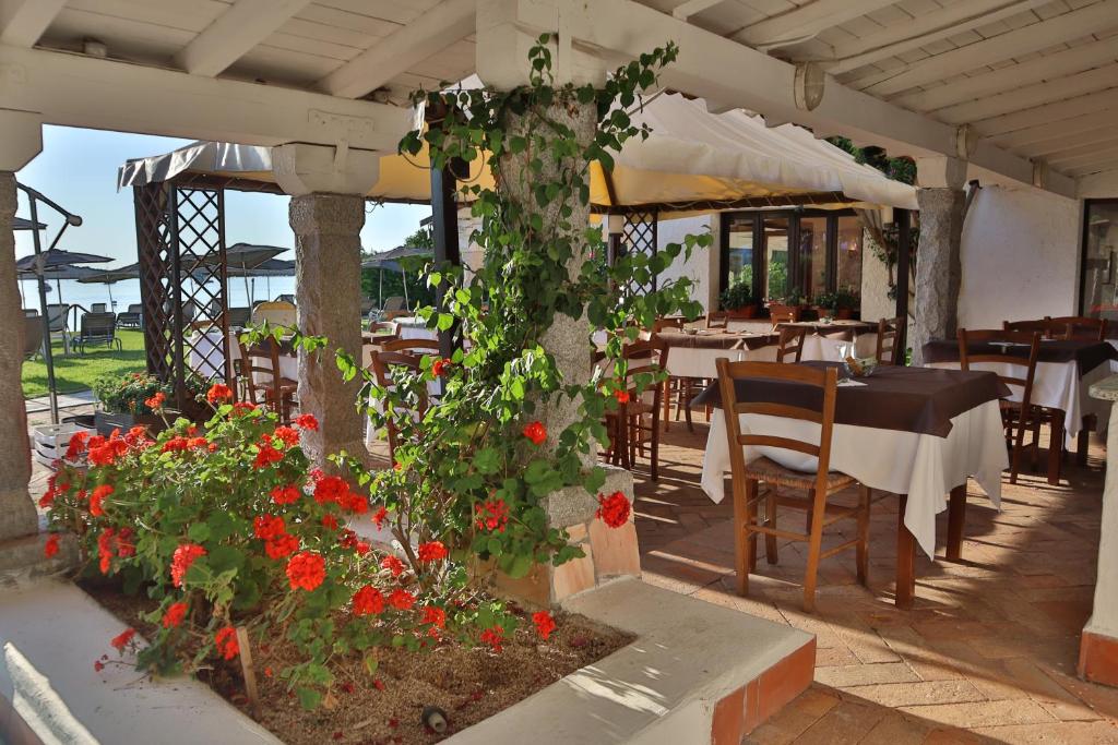 d'une terrasse avec des tables, des chaises et des fleurs rouges. dans l'établissement IHR Hotel San Paolo, à Porto San Paolo