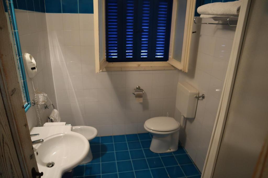 une salle de bain avec des toilettes blanches et un lavabo dans l'établissement IHR Hotel San Paolo, à Porto San Paolo