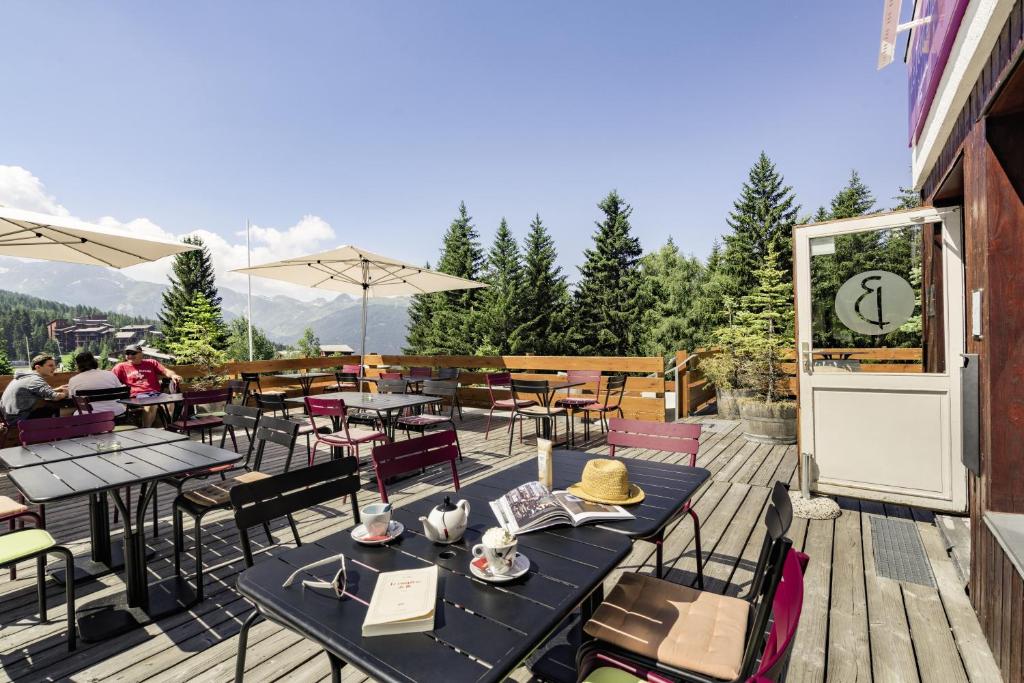 un patio avec tables et chaises sur une terrasse dans l'établissement Belambra Clubs Arc 1800 - Hôtel Du Golf, à Arc 1800