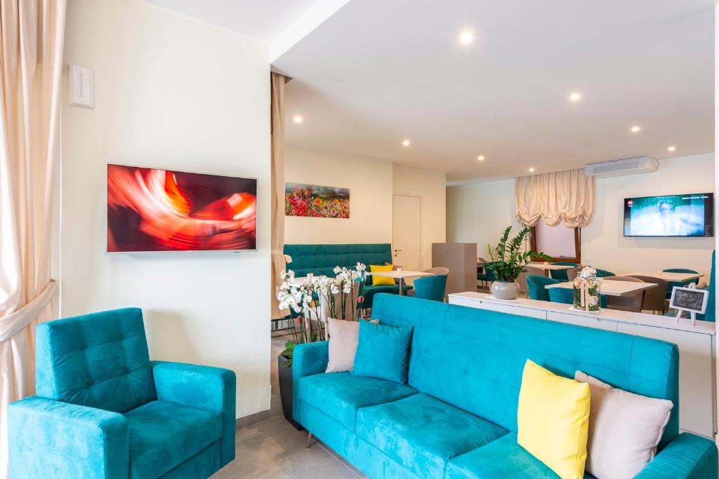 un salon avec un canapé bleu et des chaises dans l'établissement Hotel Firenze 3 Stelle Superior, à Brenzone