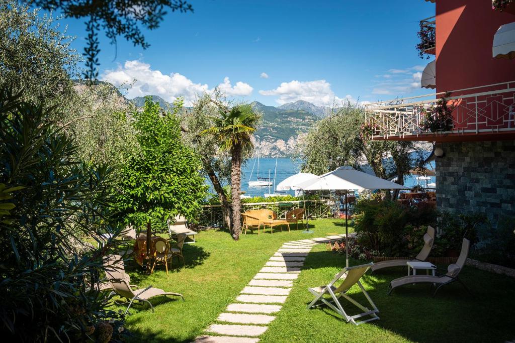 - un jardin avec des chaises et des tables et une vue sur l'eau dans l'établissement Hotel Firenze 3 Stelle Superior, à Brenzone