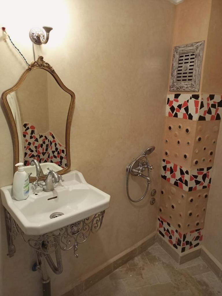 une salle de bain avec un lavabo, un miroir et une douche dans l'établissement RIAD LA SANTA, à Chefchaouen