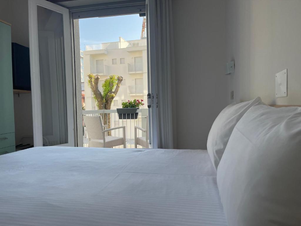 une chambre avec un lit blanc et une grande fenêtre dans l'établissement Hotel Athena, à Lignano Sabbiadoro