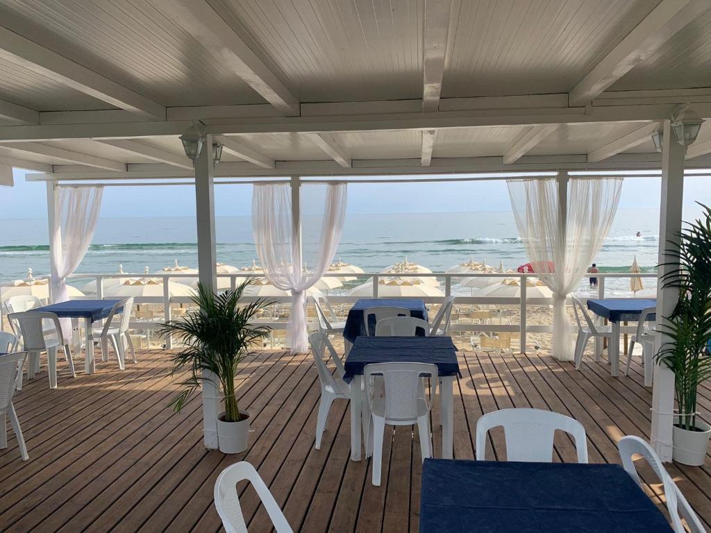une terrasse avec des tables et des chaises et la plage dans l'établissement Ganimede Hotel, à Sperlonga