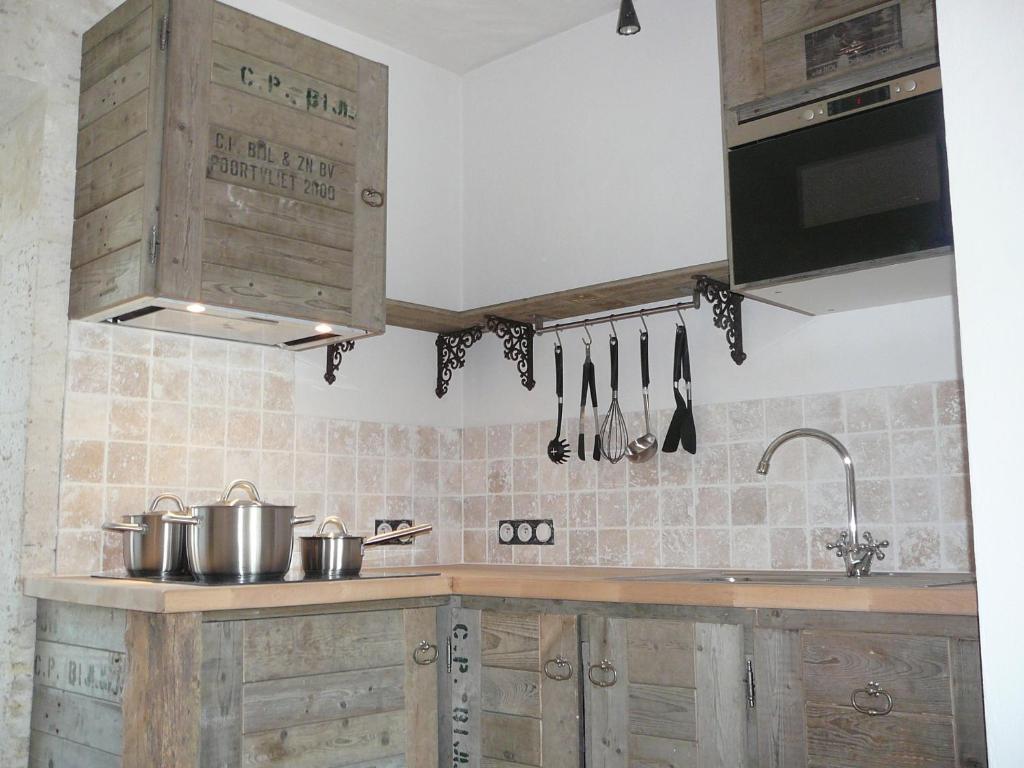 une cuisine avec des armoires en bois et un évier dans l'établissement Gites Loste, à Beauville
