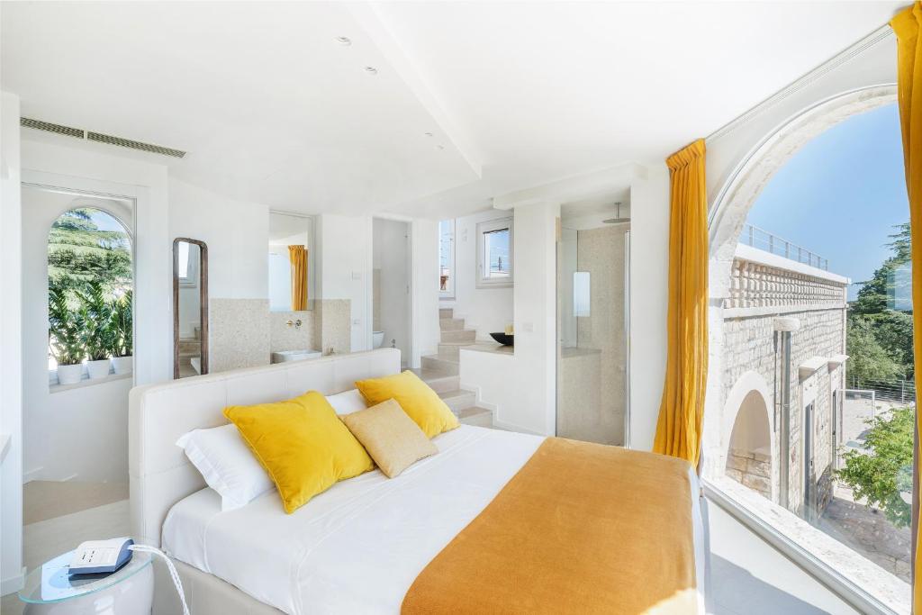 - une chambre blanche avec un lit blanc et des oreillers jaunes dans l'établissement Villa Lemorè, à Fasano