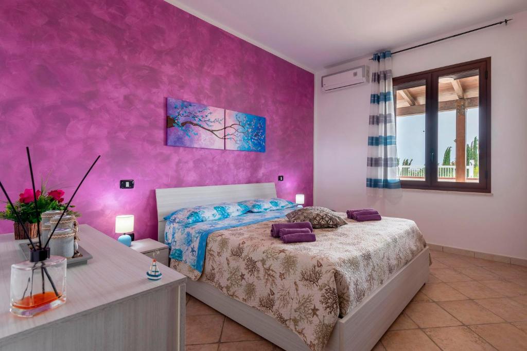 une chambre avec un lit et un mur rose dans l'établissement Casa Vacanza Errante, à Menfi