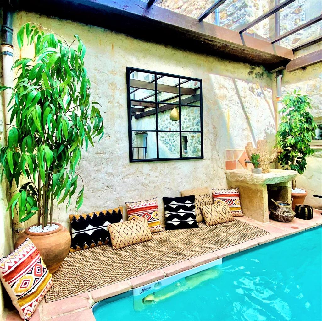 d'une terrasse avec un canapé à côté de la piscine. dans l'établissement Gîte de groupe 15p-9ch OU 3 gîtes indépendants 5p-3ch - PATIO et PISCINE INTERIEURE CHAUFFEE TOUTE L'ANNEE, à Vallon-Pont-dʼArc