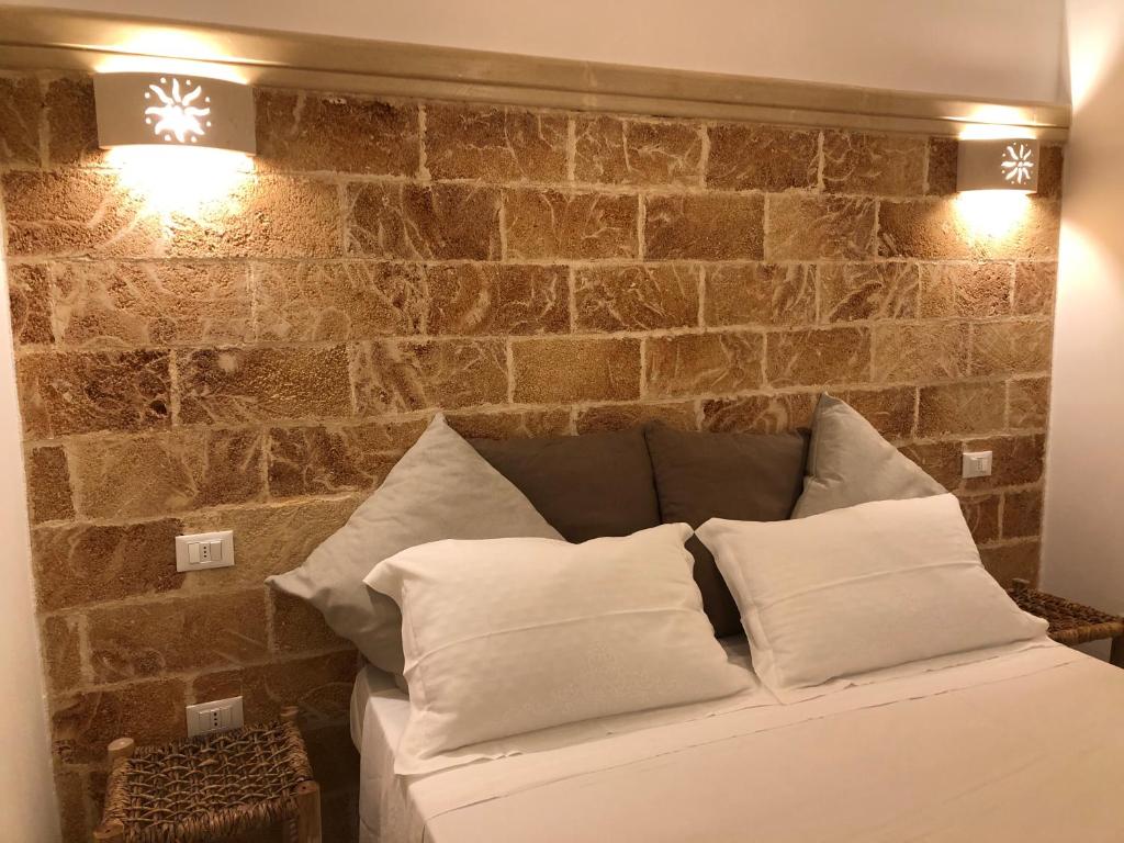 - un canapé avec des oreillers en face d'un mur en briques dans l'établissement Cottage Vittoria - Marina di Novaglie, à Gagliano del Capo