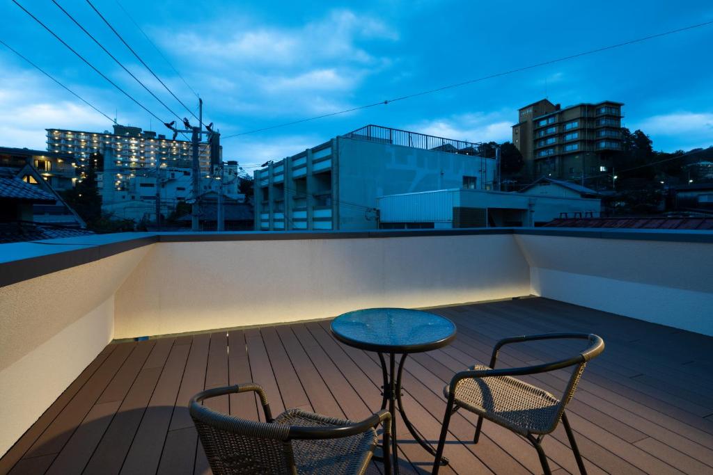 d'un balcon avec deux chaises et une table sur le toit. dans l'établissement Arima Koyado Uraku, à Kobe 17 autres photos