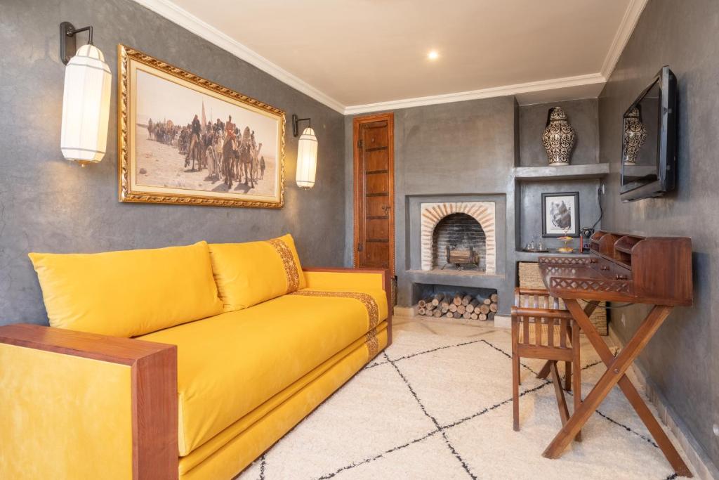- un canapé jaune dans le salon avec cheminée dans l'établissement Riad Alma, à Marrakech
