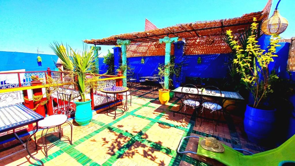 une terrasse avec des chaises et des tables ainsi qu'un bâtiment bleu dans l'établissement Riad Rêve d Antan, à Marrakech