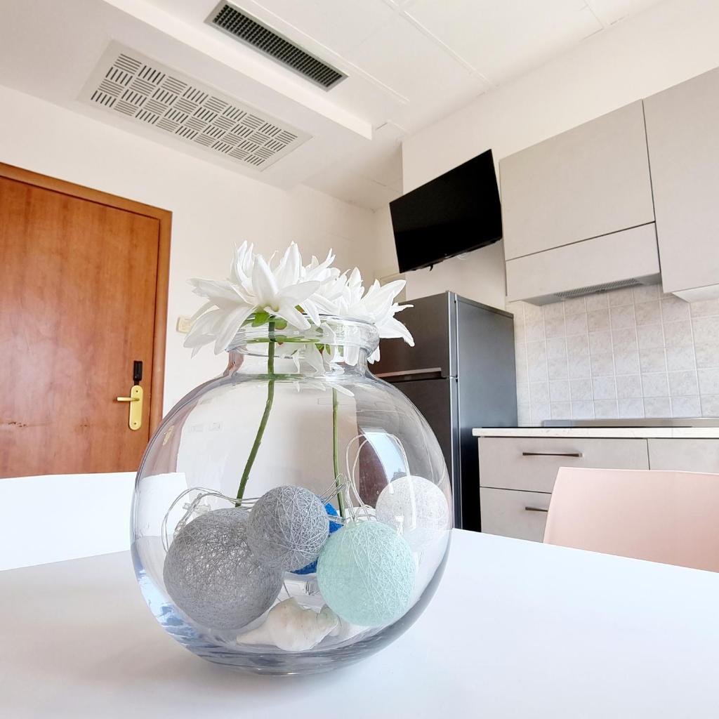 un vase en verre clair avec des fleurs blanches dans la cuisine dans l'établissement Residence Mare, à Rimini