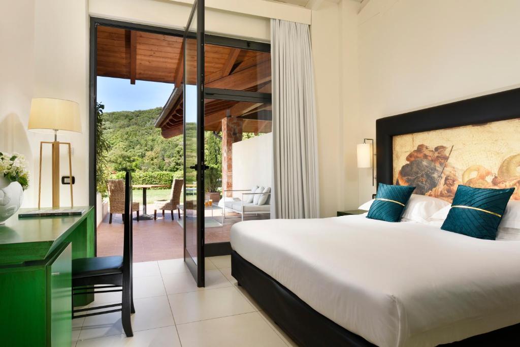 une chambre avec un grand lit et un balcon dans l'établissement Argentario Lagoon Resort & Spa, à Monte Argentario