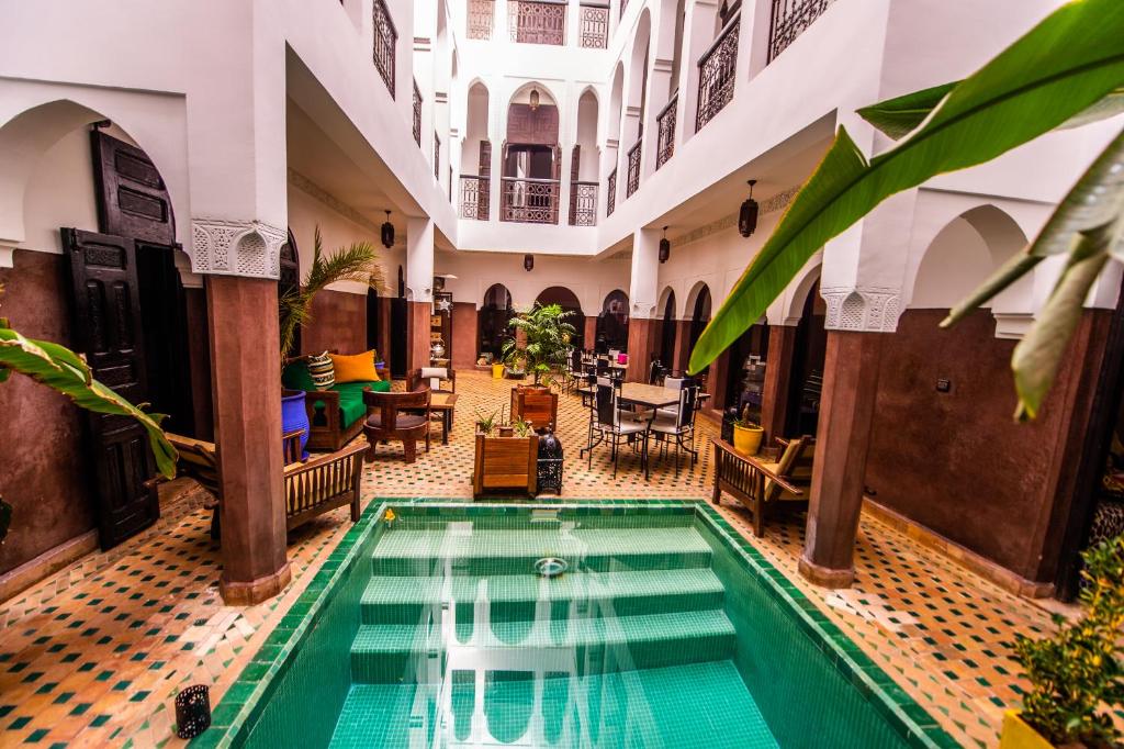 une piscine intérieure dans un bâtiment avec tables et chaises dans l'établissement Riad Khabia & Spa, à Marrakech