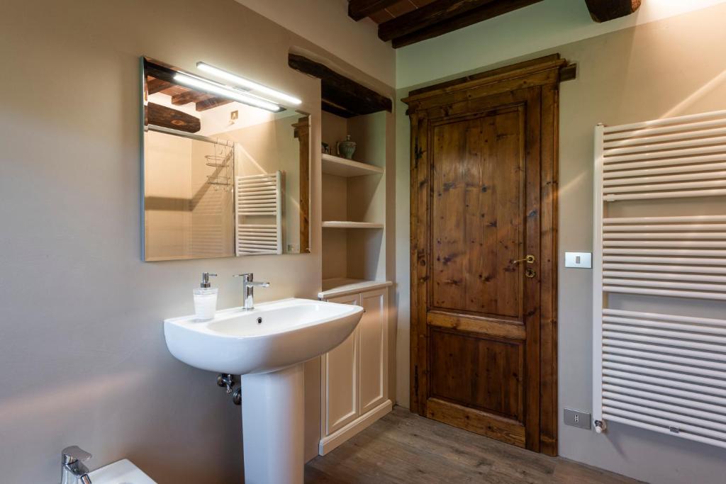 La salle de bains est pourvue d'un lavabo et d'une porte en bois. dans l'établissement Villa la Ghiandaia by Mmega, à Pergognano