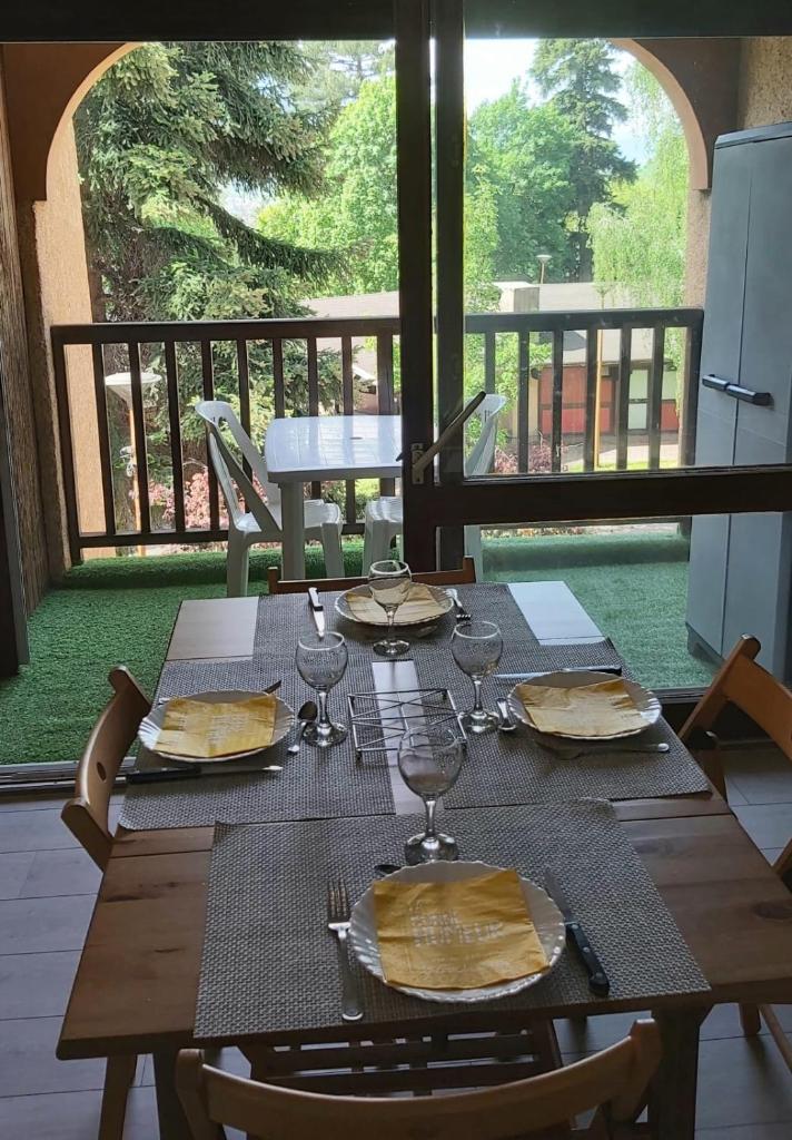 une table en bois avec des assiettes et des verres à vin dessus dans l'établissement Beautiful studio with balcony in Briançon, à Briançon