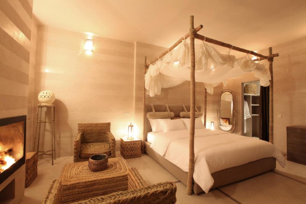 une chambre avec un lit à baldaquin et une cheminée dans l'établissement Riad Joya, à Marrakech