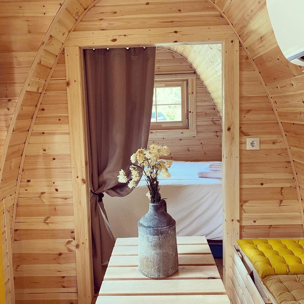 Cette petite chambre se trouve dans une cabane en bois avec un vase sur une table. dans l'établissement Camping La Ferme de Castellane, à Castellane