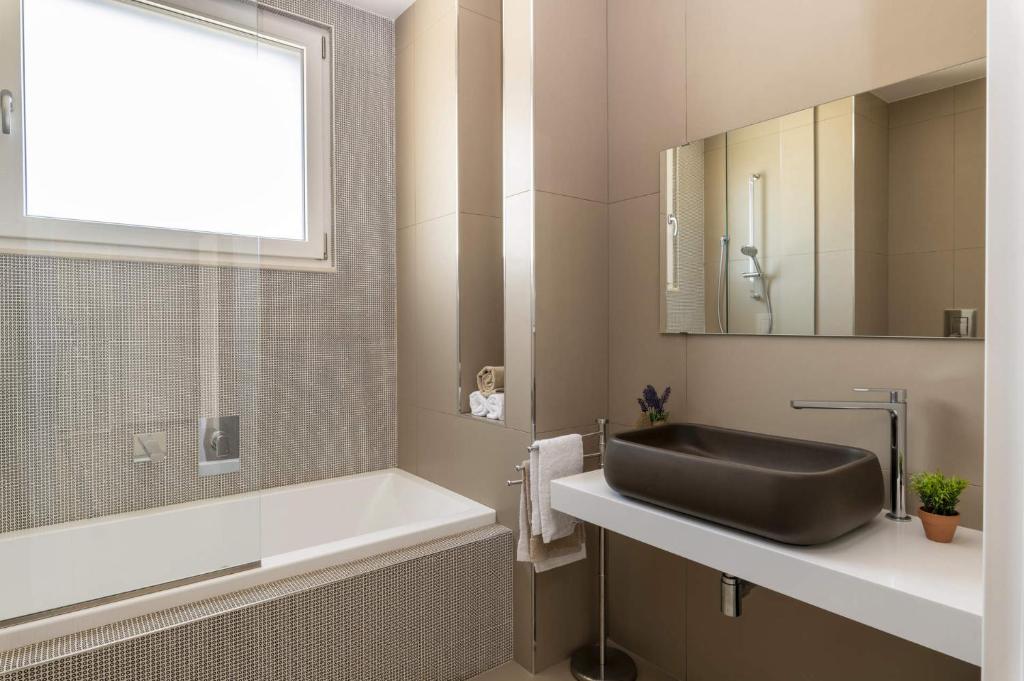 La salle de bains est pourvue d'un lavabo noir et d'une baignoire. dans l'établissement Villa Campanella by Villa Plus, à Noci