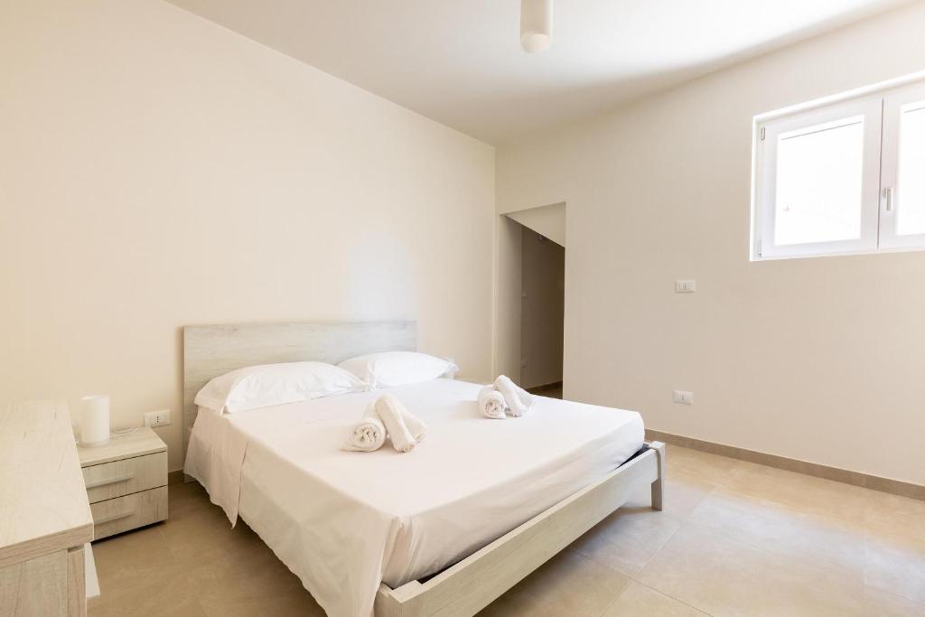 une chambre blanche avec un lit avec des serviettes dessus dans l'établissement Villa La Seta by Perle di Puglia, à San Vito dei Normanni