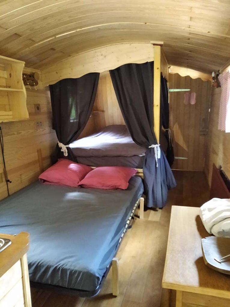 - un lit dans une petite maison avec une table dans l'établissement Belle Roulotte unique en pleine campagne Au Jardin de la Vouivre, à Saint-Vincent-en-Bresse 37 autres photos