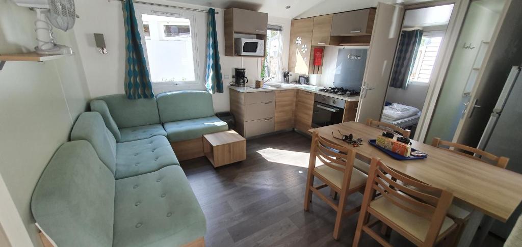 une petite cuisine et salle à manger avec une table et des chaises dans l'établissement MH 150 camping 4 etoiles Bois Dormant 4 personnes, à Saint-Jean-de-Monts