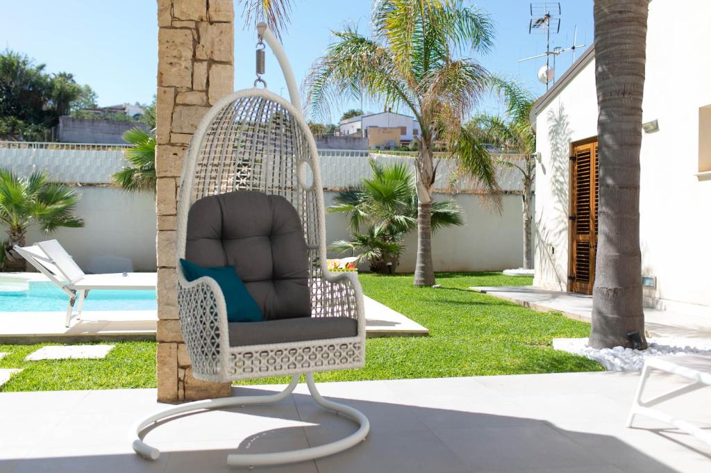une chaise en rotin blanc assise à côté de la piscine dans l'établissement Villa Perla del Mare, à Alcamo Marina 43 autres photos